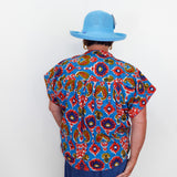 Person wearing a colorful patterned shirt and blue hat against a white background