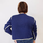 Person wearing a blue pinstripe shirt with white trim on a plain background