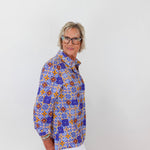 Person wearing a colorful patterned shirt against a white background