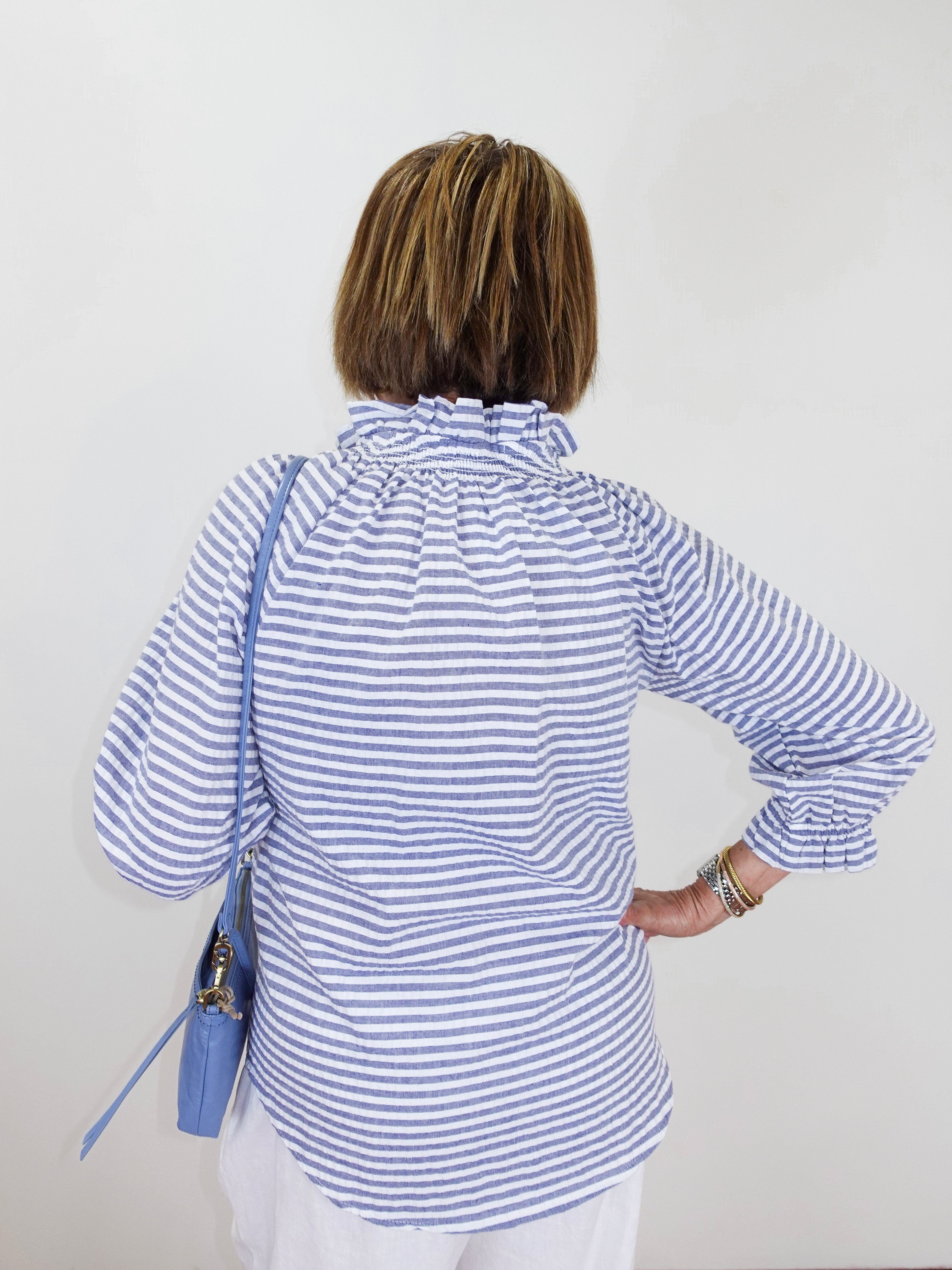 Person wearing a blue and white striped shirt with a white background
