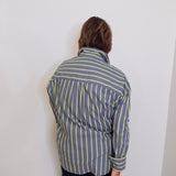 Person wearing a blue and white striped shirt against a white wall
