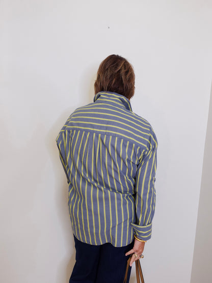 Person wearing a blue and white striped shirt against a white wall
