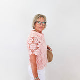 Woman wearing a pink floral top and white pants against a white background