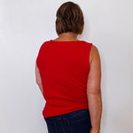 Person wearing a red sleeveless top and dark blue jeans against a white background