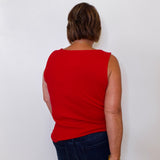 Person wearing a red sleeveless top and dark blue jeans against a white background