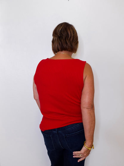Person wearing a red sleeveless top and dark blue jeans against a white background
