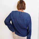 Person wearing a blue denim shirt against a white background