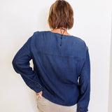 Person wearing a blue denim shirt against a white background