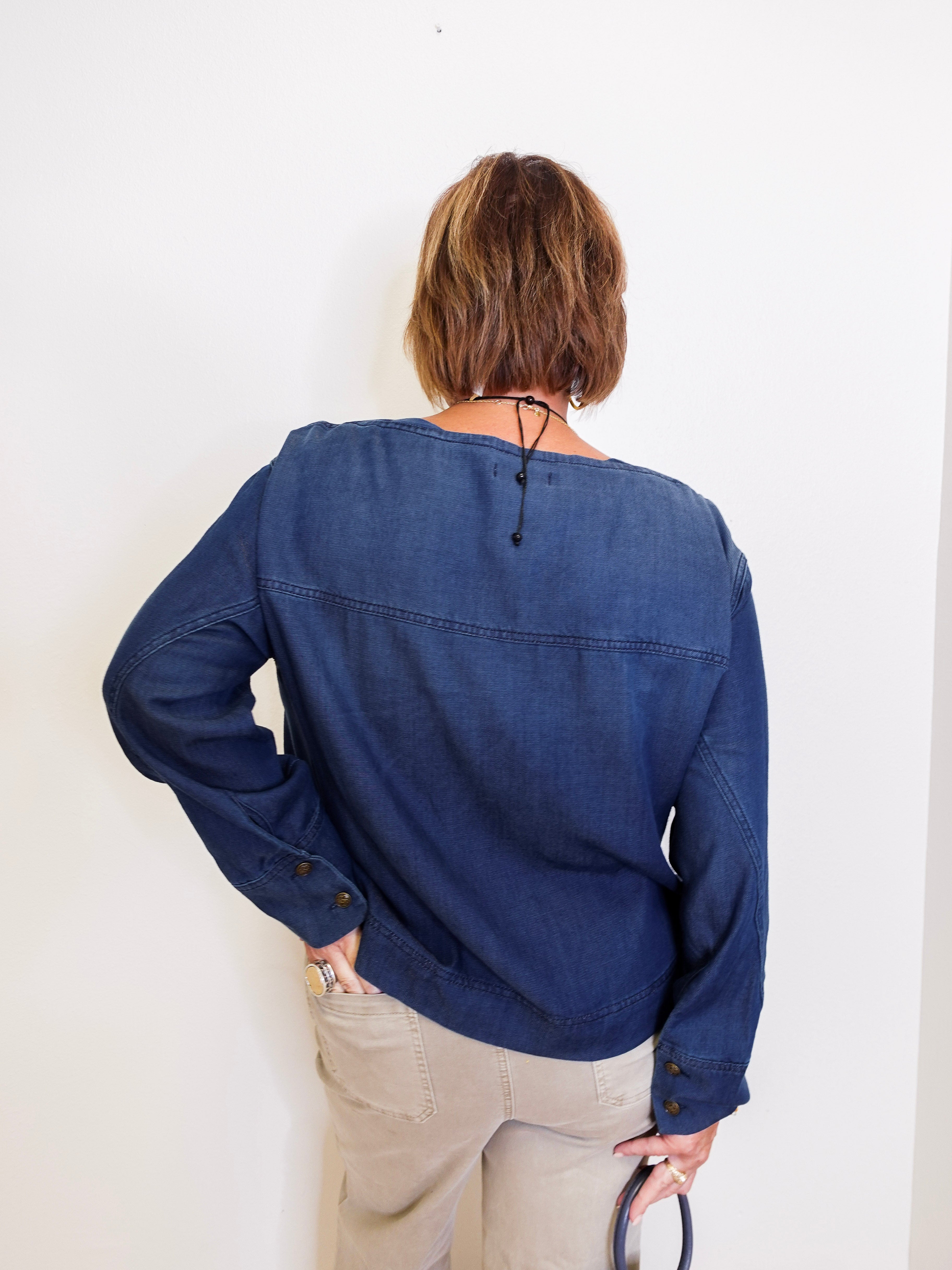 Person wearing a blue denim shirt against a white background