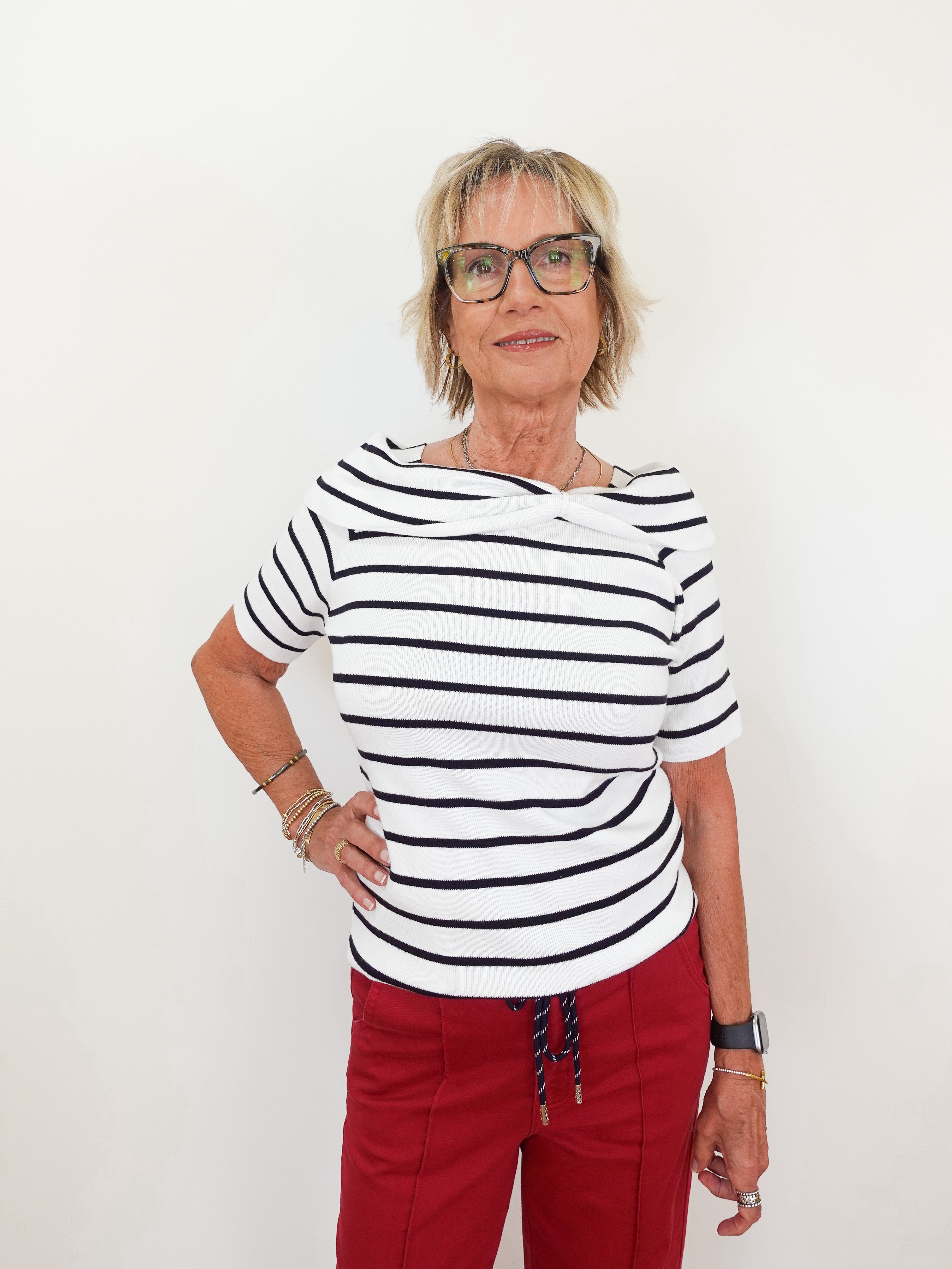 Woman wearing a striped shirt and red pants against a white background