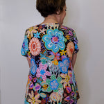 Person wearing a colorful floral dress against a white wall