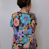 Person wearing a colorful floral dress against a white wall