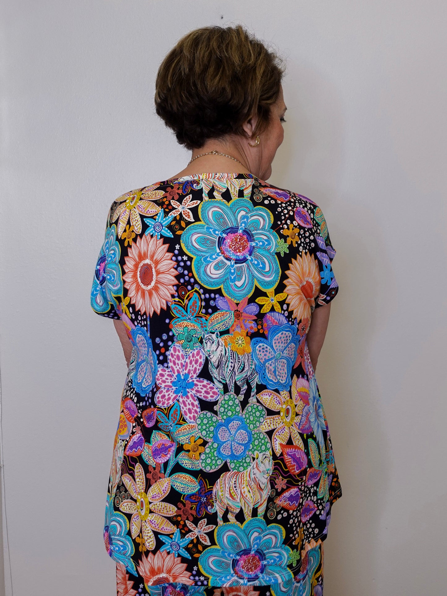 Person wearing a colorful floral dress against a white wall