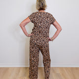 Person wearing a leopard print outfit standing against a white wall.