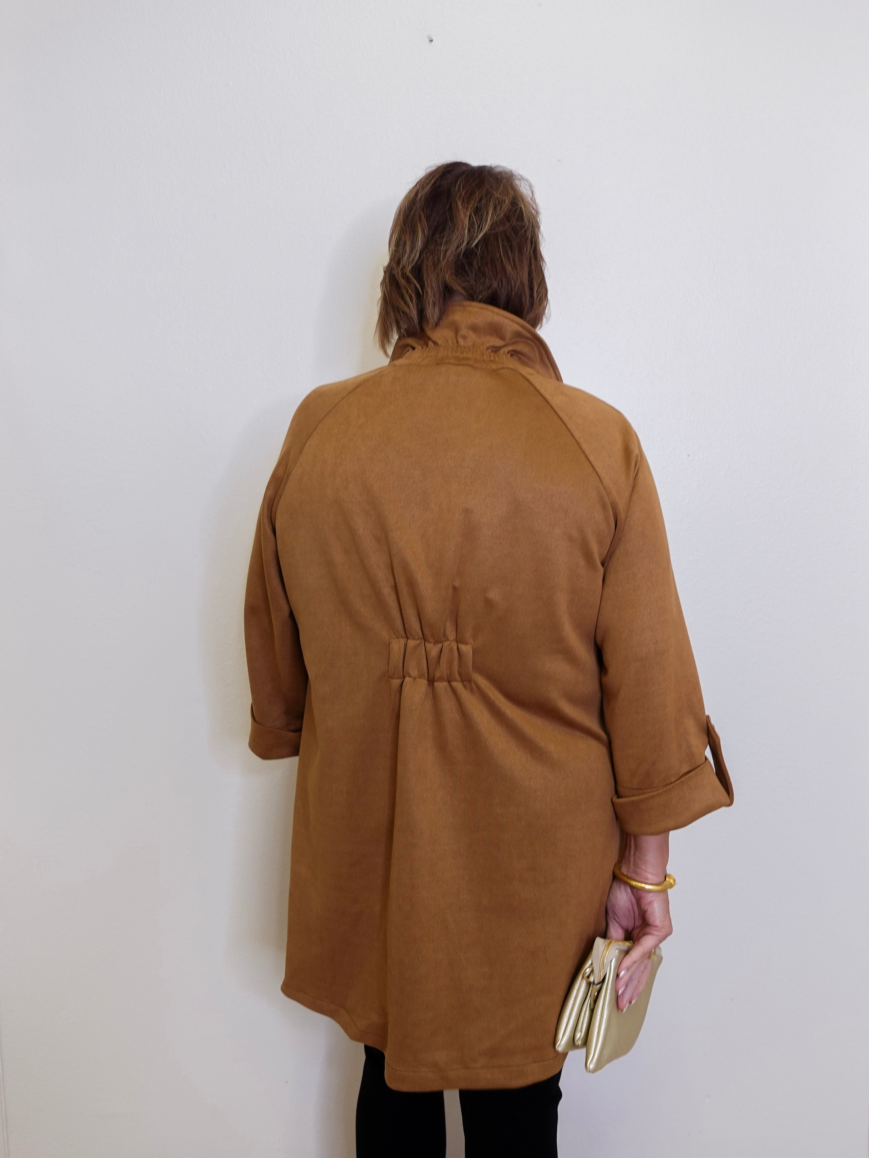 Person wearing a brown coat against a white wall