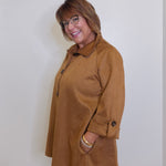Woman wearing a brown coat against a white background
