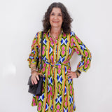 Woman wearing a colorful patterned dress against a white background