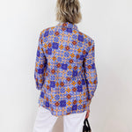 Person wearing a colorful patterned shirt against a white background