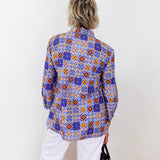 Person wearing a colorful patterned shirt against a white background