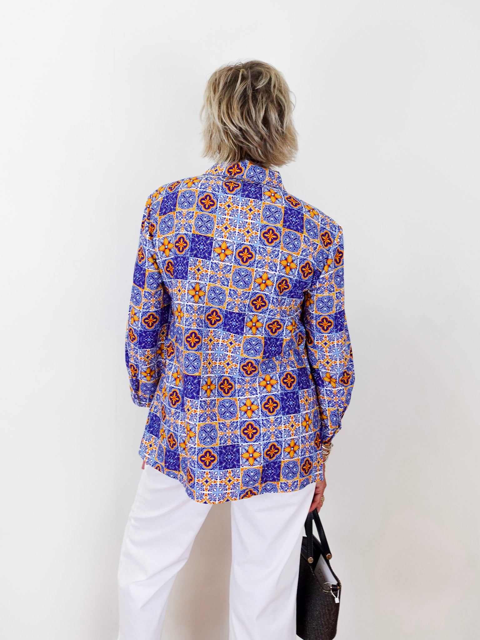 Person wearing a colorful patterned shirt against a white background