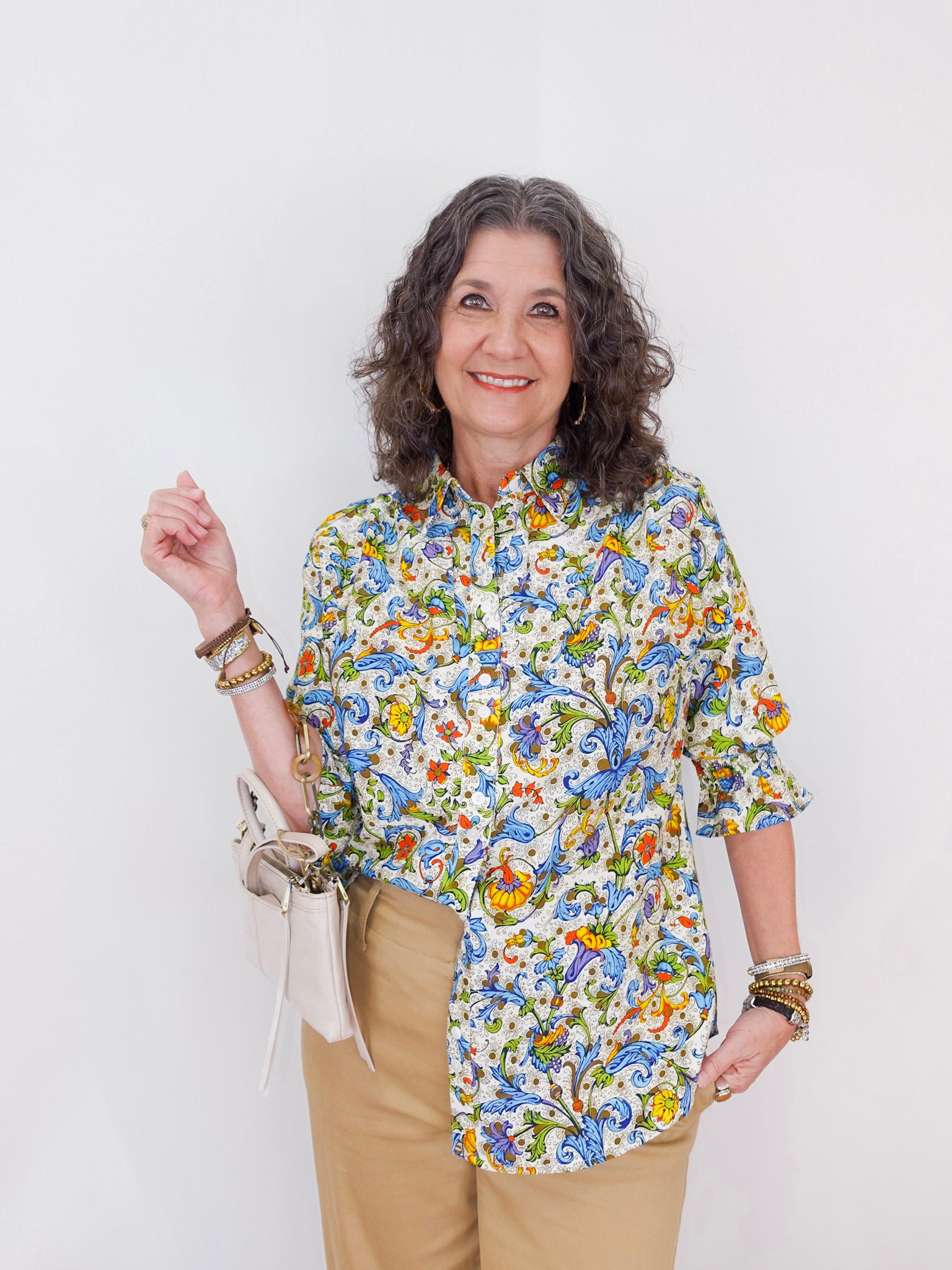 Woman wearing a colorful floral shirt against a white background