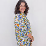 Woman wearing a colorful floral blouse against a white background