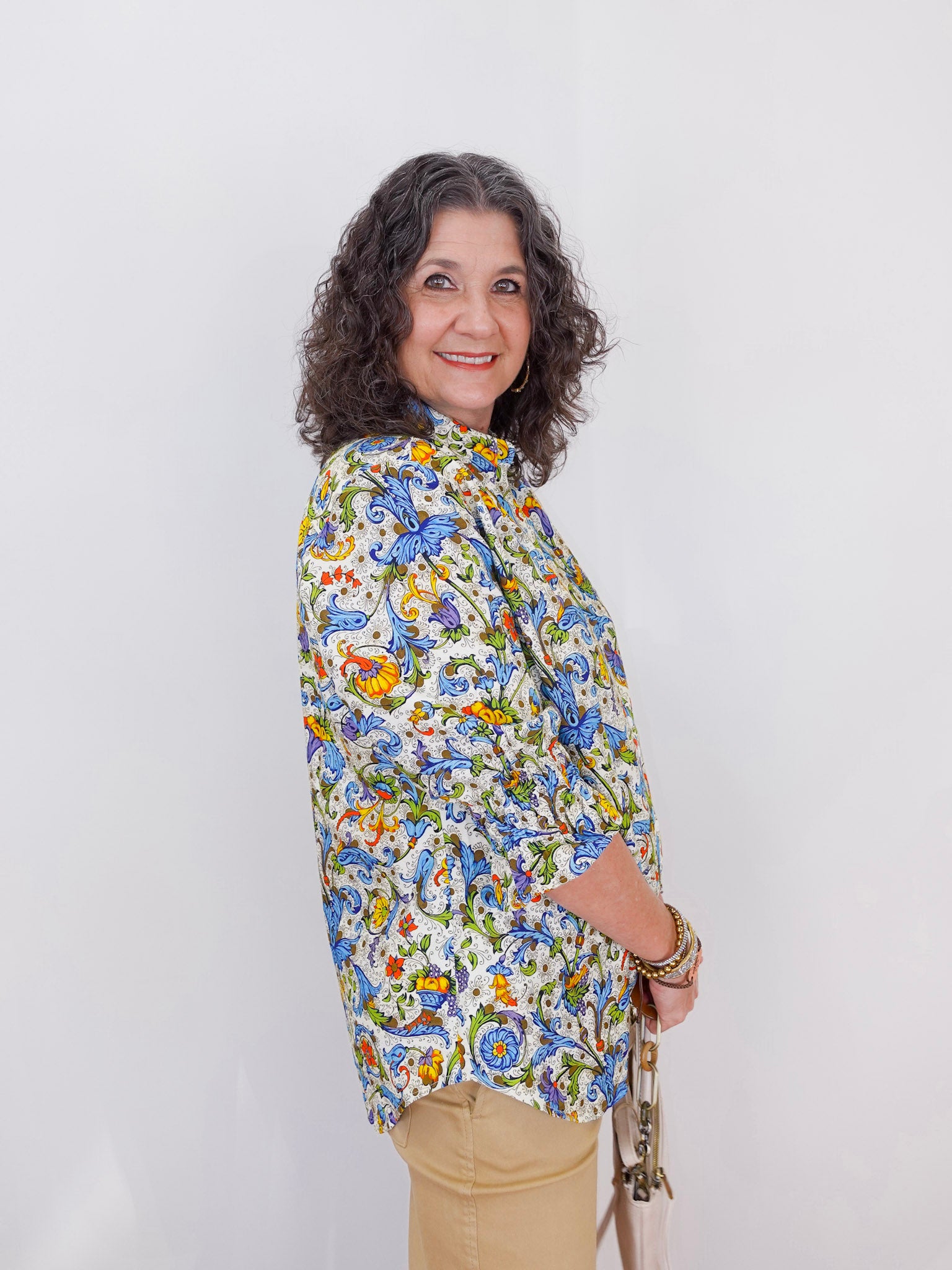 Woman wearing a colorful floral blouse against a white background
