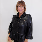 Woman wearing a black leather jacket with ruffled details against a white background