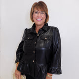 Woman wearing a black leather jacket with ruffled details against a white background