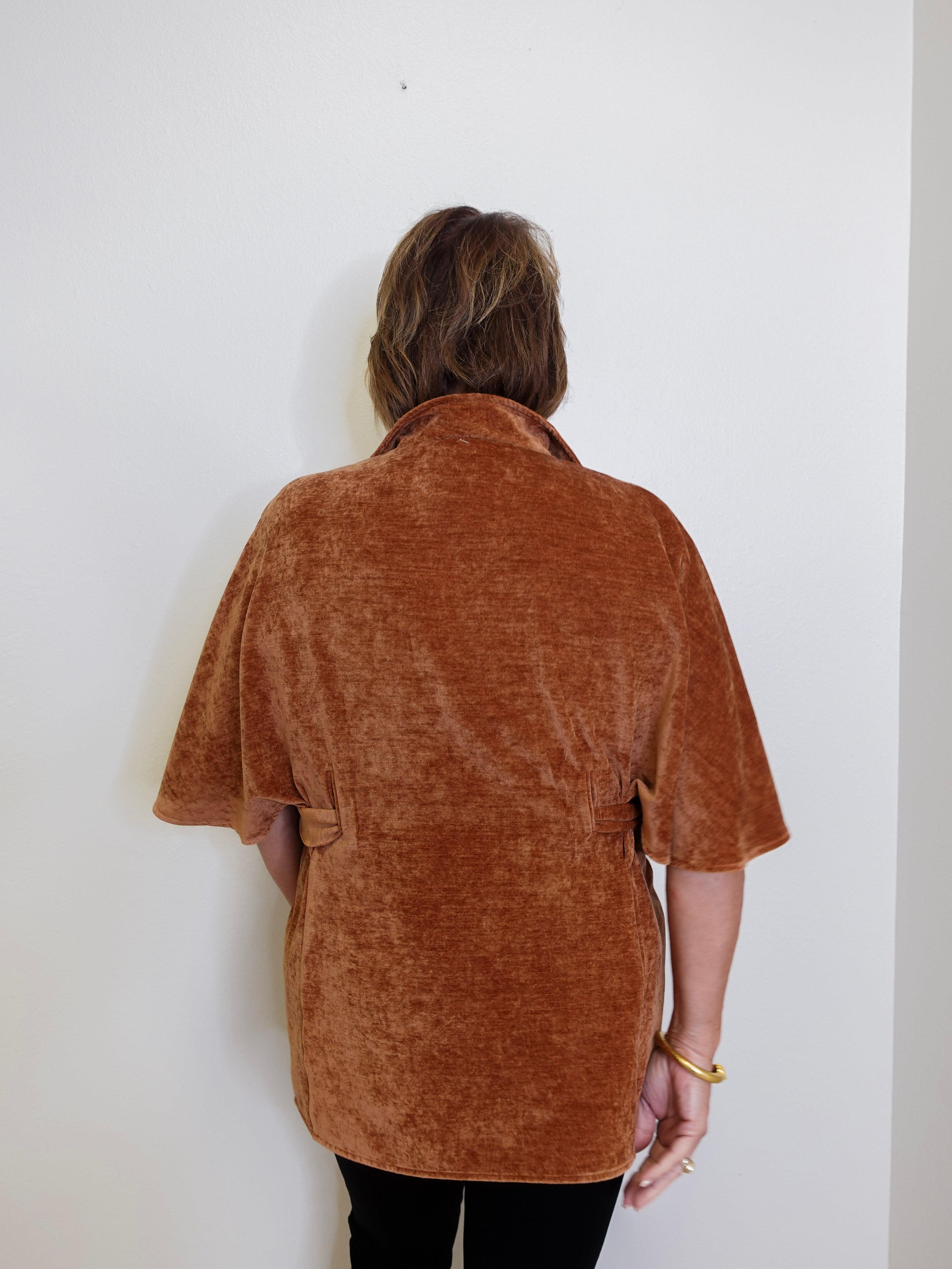 Person wearing a brown textured shirt against a white wall