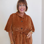 Woman wearing a brown jacket with a plain background