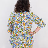Person wearing a colorful floral blouse against a white background