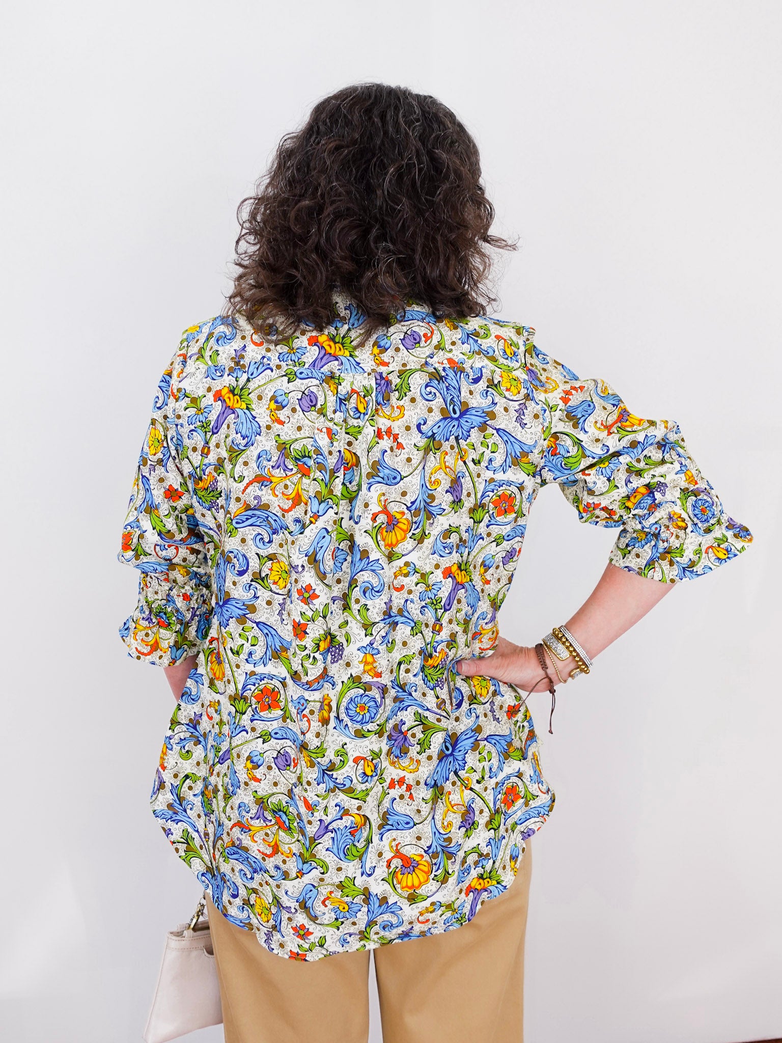 Person wearing a colorful floral blouse against a white background