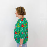 Person wearing a green floral blouse against a white background