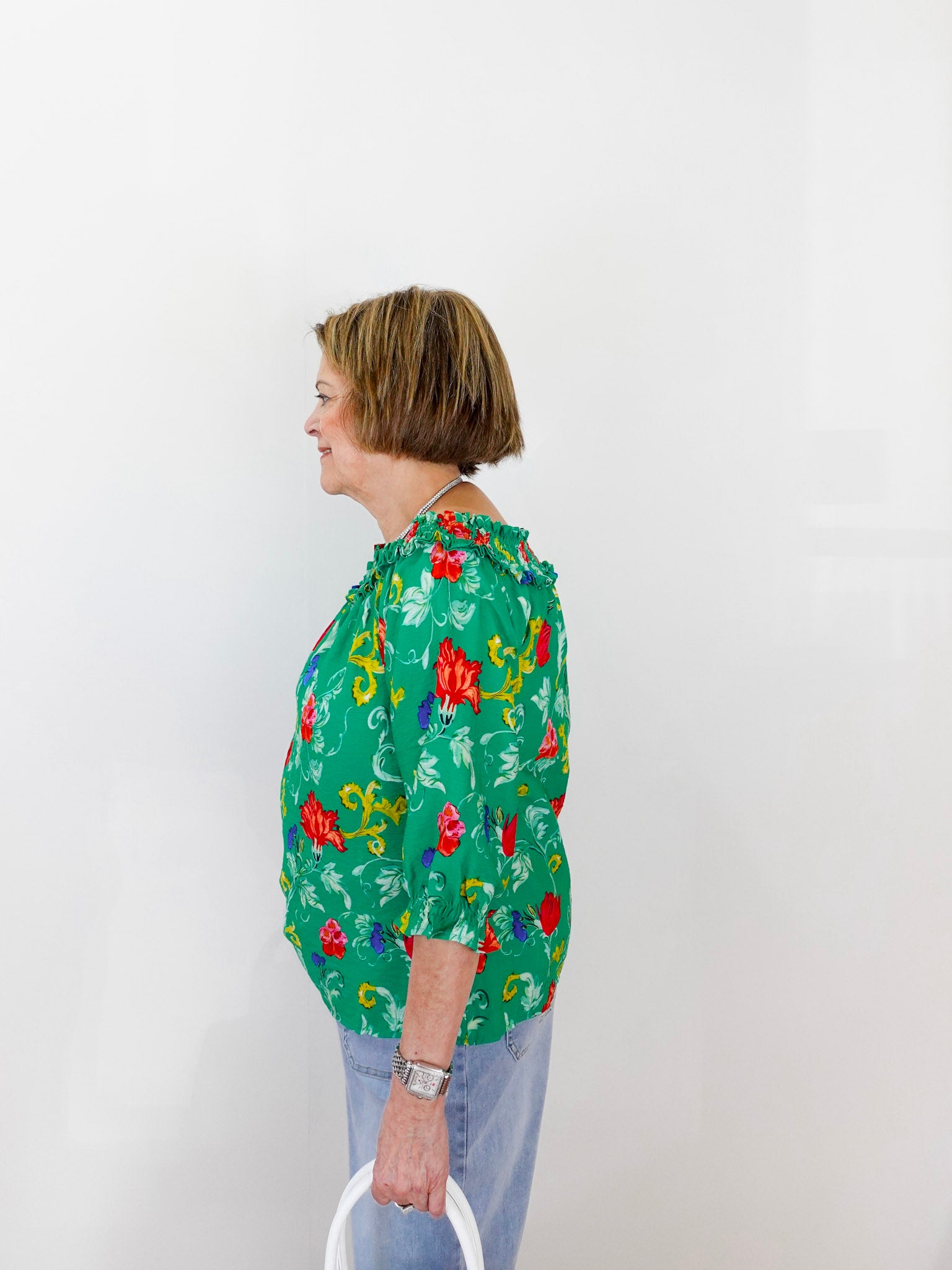 Person wearing a green floral blouse against a white background