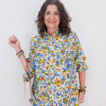 Woman wearing a colorful floral blouse against a white background