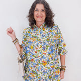 Woman wearing a colorful floral blouse against a white background