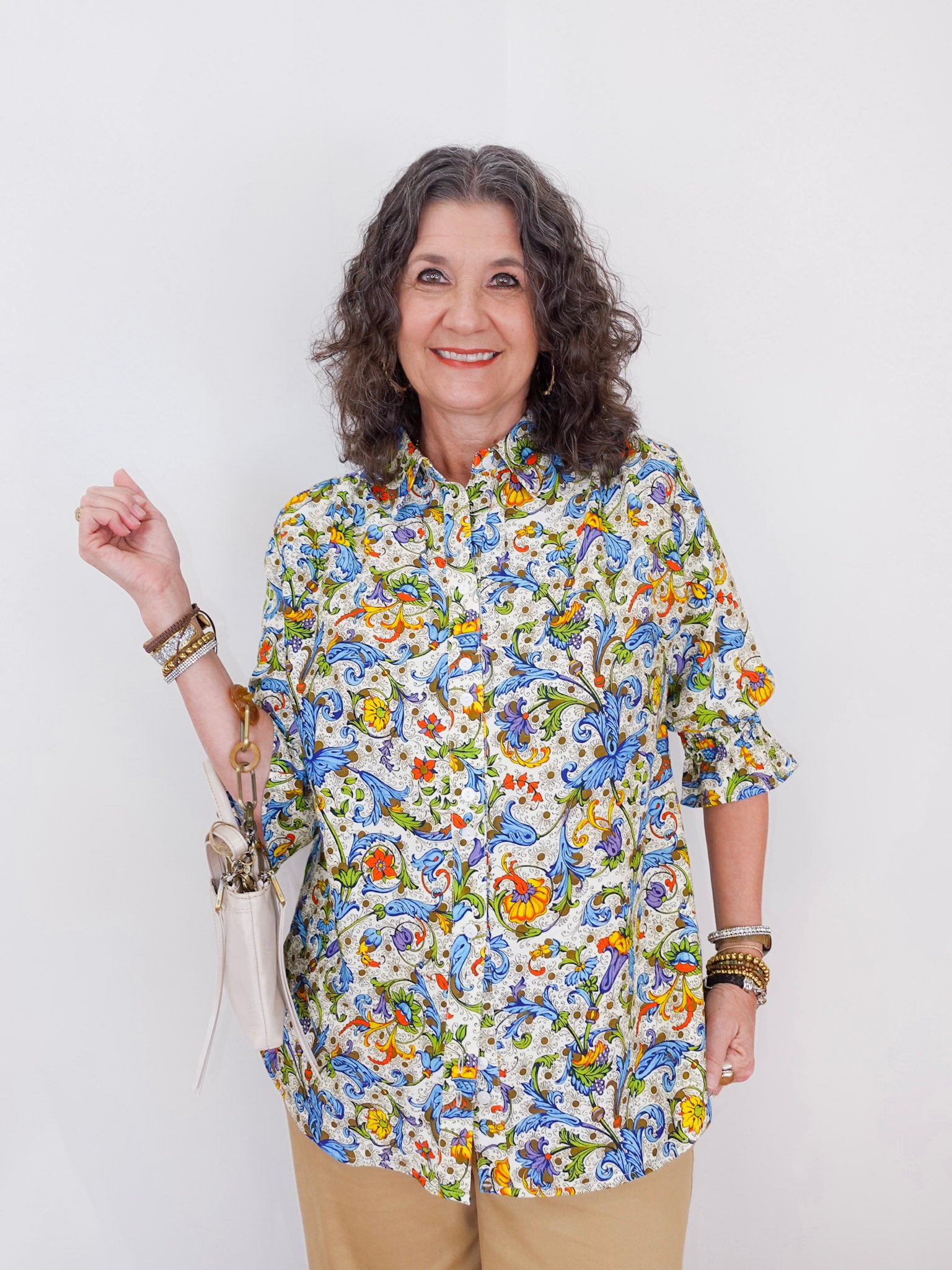 Woman wearing a colorful floral blouse against a white background