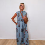 Woman wearing a blue floral jumpsuit against a white wall
