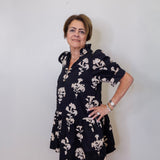Woman wearing a navy floral dress against a white wall