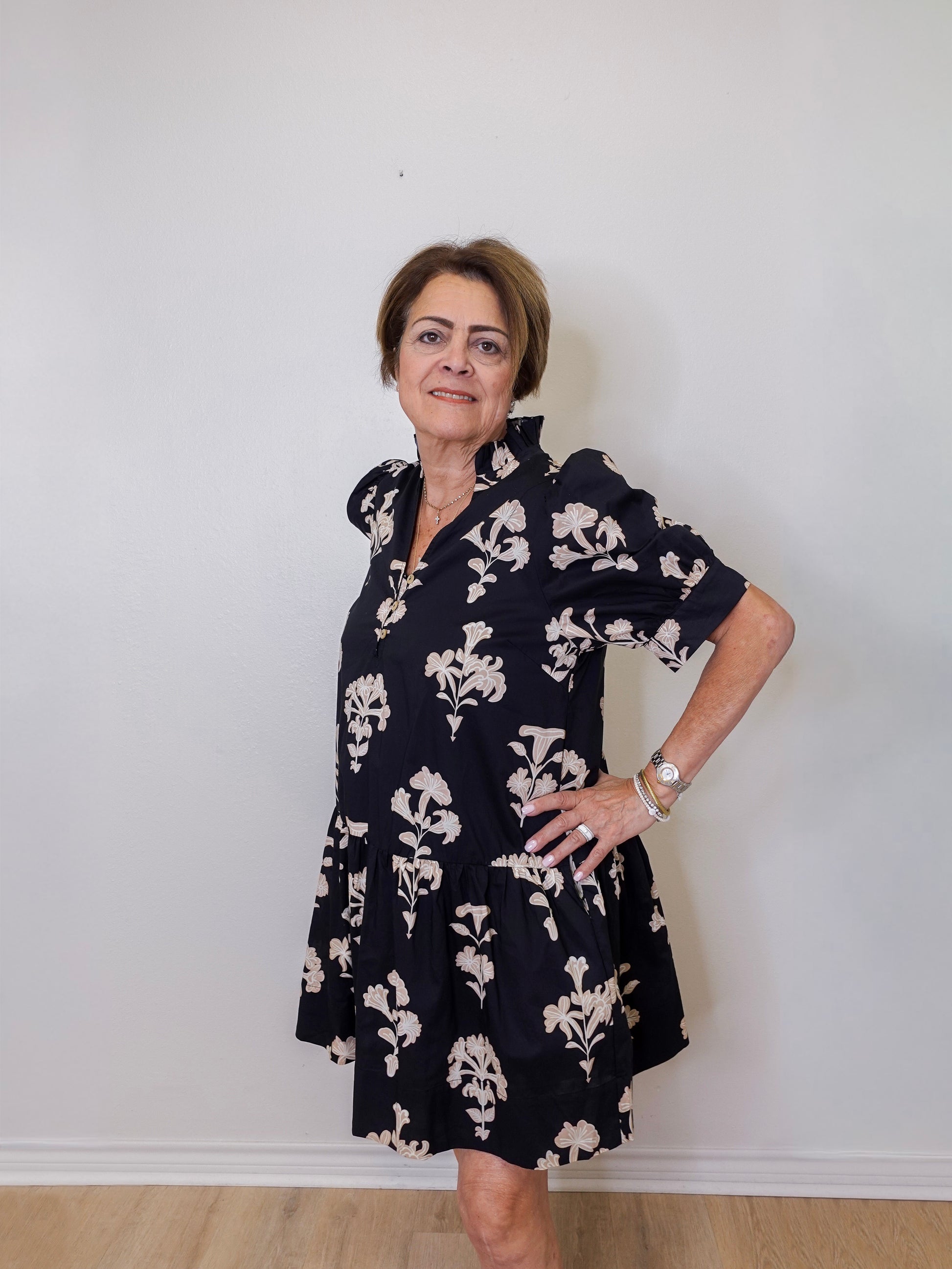Woman wearing a navy floral dress against a white wall