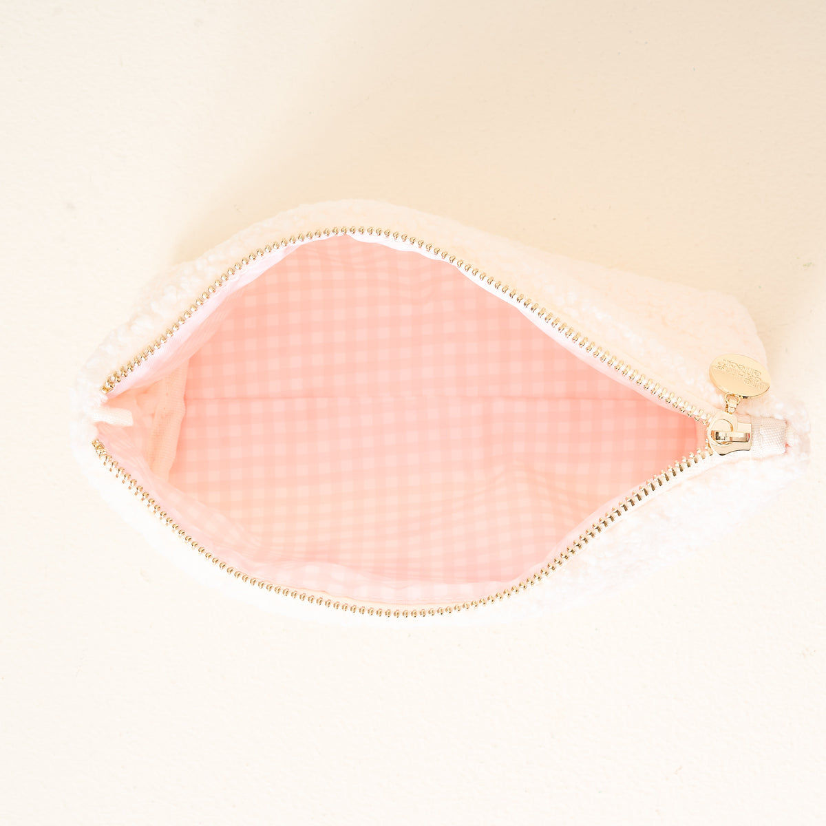 Pink makeup pouch with gold zipper on a light beige background