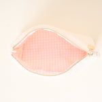 Pink makeup pouch with gold zipper on a light beige background
