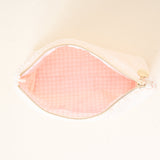 Pink makeup pouch with gold zipper on a light beige background