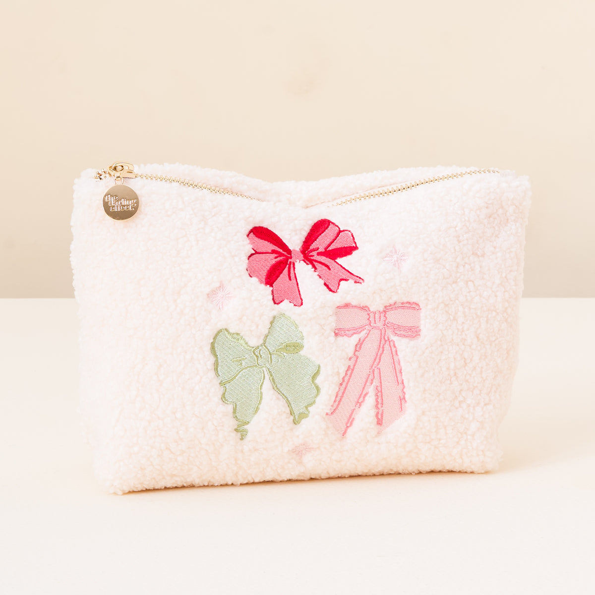 White pouch with pink bows and a green butterfly on a beige background
