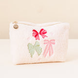 White pouch with pink bows and a green butterfly on a beige background