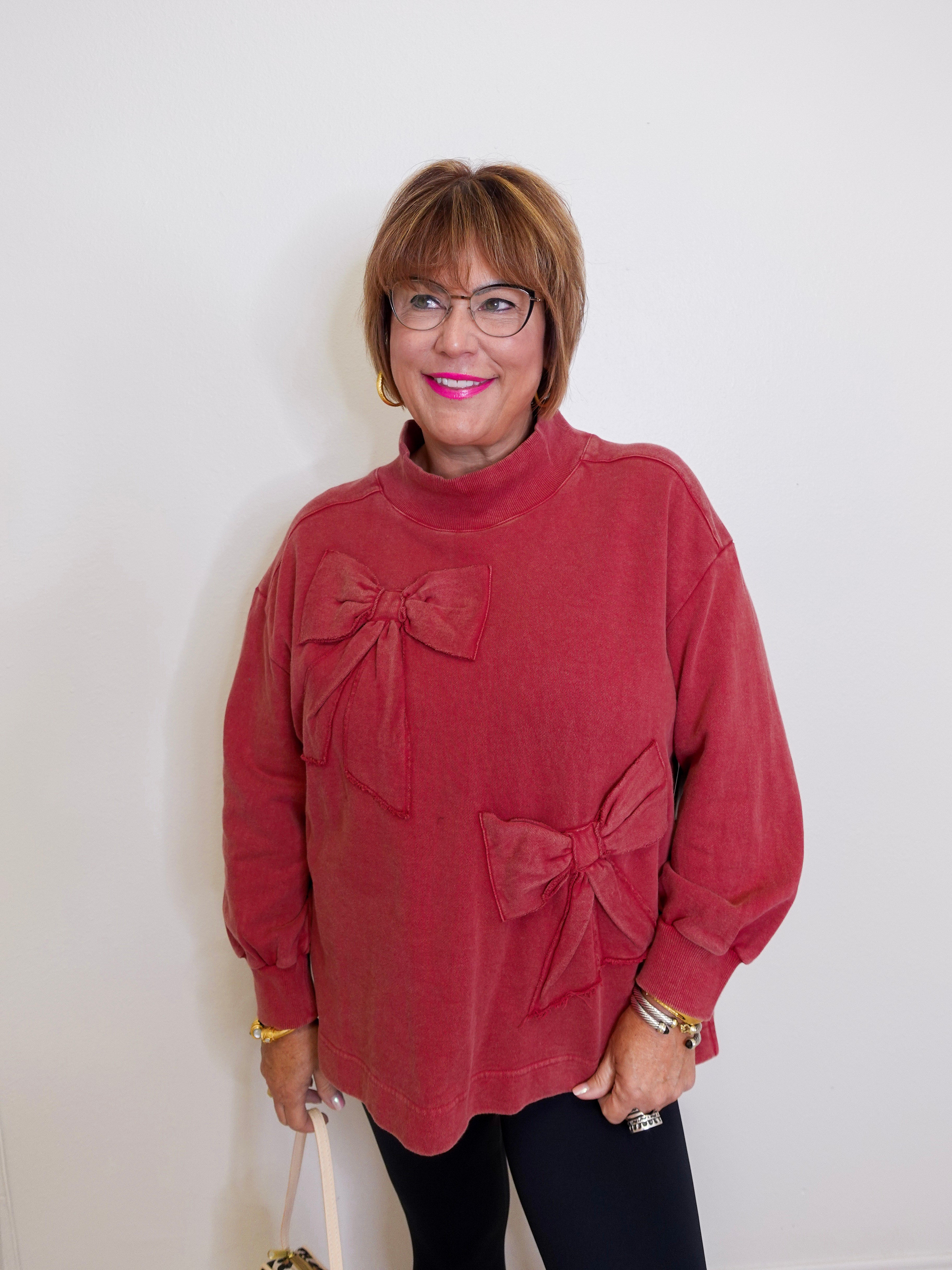 Woman wearing a red sweater with bow details against a white background