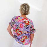 Person wearing a colorful floral blouse against a white background