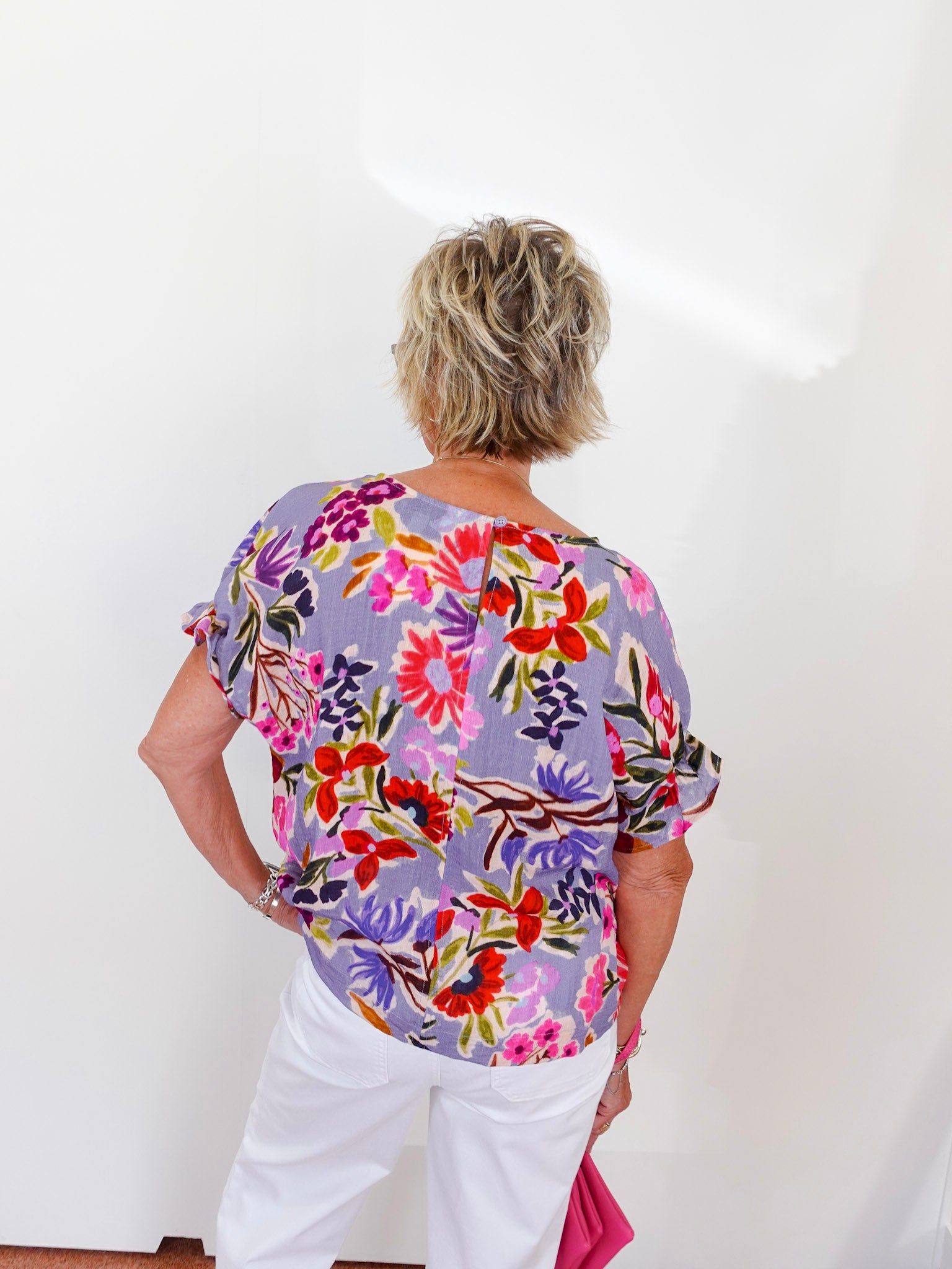 Person wearing a colorful floral blouse against a white background
