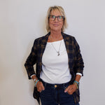 Woman wearing a plaid jacket, white shirt, and blue jeans against a plain background